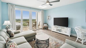 Una sala de estar con sofá, mesa de centro, televisor y balcón con vistas.