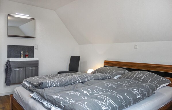 A bedroom with a bed, a nightstand, a chair, a mirror, and a small cabinet.