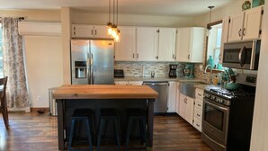 Una cocina moderna con una isla central, electrodomésticos de acero inoxidable y suelo de madera.