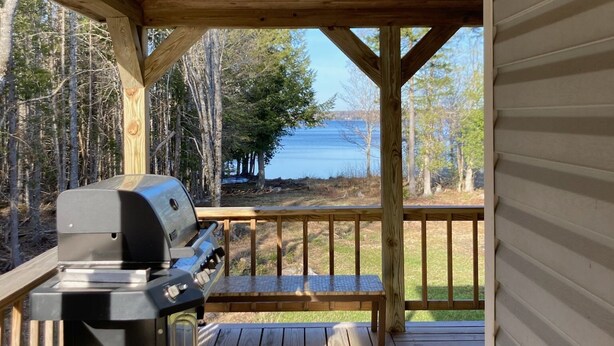 Una terraza techada con una parrilla y vistas al lago.