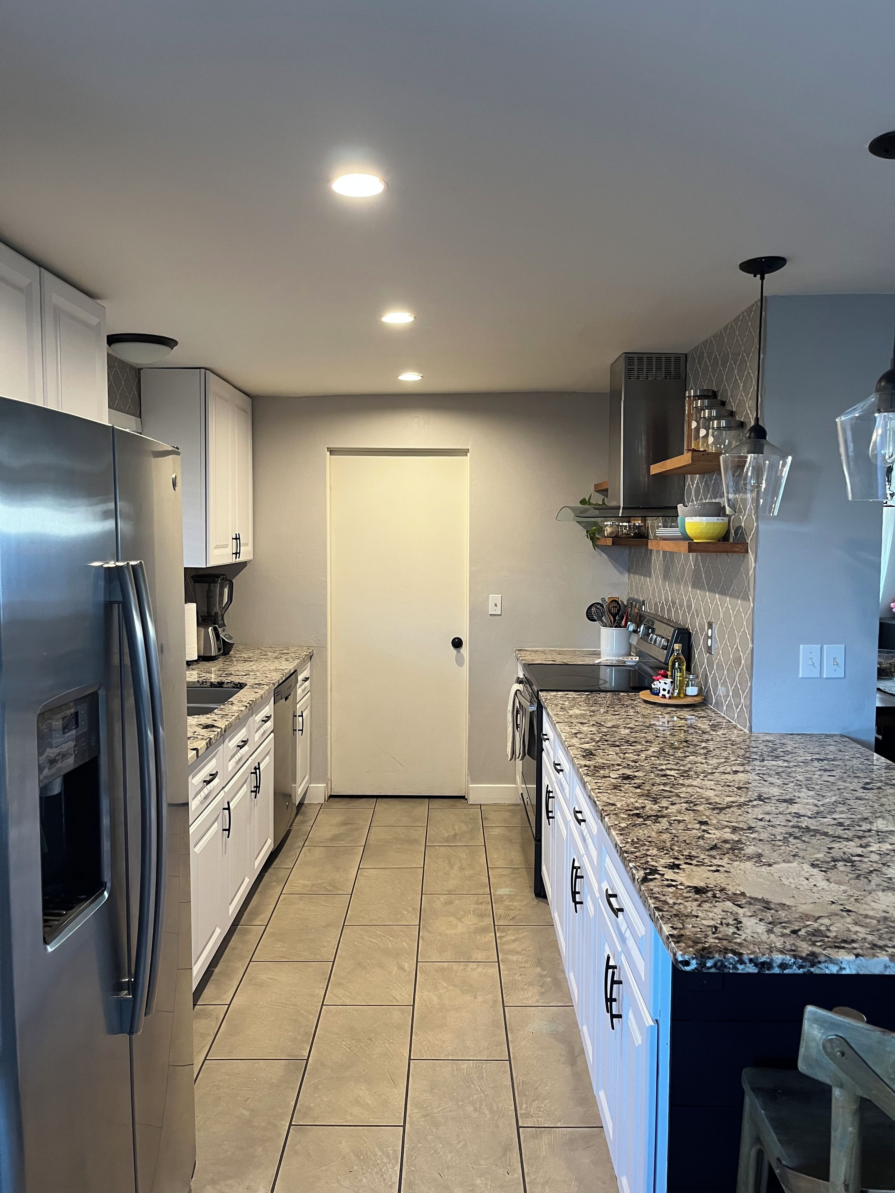 A modern kitchen with stainless steel appliances, a granite countertop, and a built-in oven.