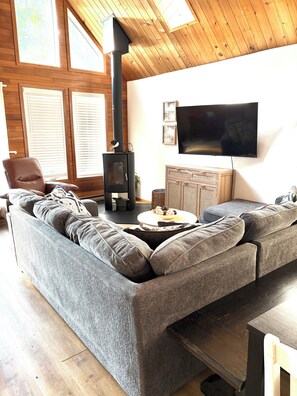 Un salon avec un canapé, un téléviseur, une cheminée et des murs en bois.