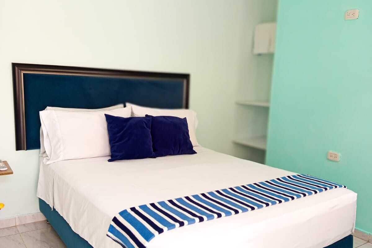 A bed with a striped blanket, a dark headboard, and white pillows.