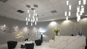 A modern lobby with a reception desk, black seating, and hanging light fixtures.
