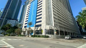 A tall, modern building with a prominent blue vertical stripe, surrounded by other high-rise buildings and palm trees.