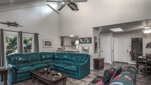 A spacious living room with a teal sectional sofa, a wooden coffee table, and a colorful patterned sofa. - Jen Casa Sue Casa - Spacious, Priv Hot Tub, TONS of Wildlife (Ruidoso)