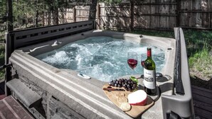 A hot tub with a wooden deck, a bottle of wine, and a cheese board with grapes and crackers. - Jen Casa Sue Casa - Spacious, Priv Hot Tub, TONS of Wildlife (Ruidoso)