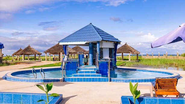 A pool area with a gazebo, lounge chairs, and thatched-roof structures. - Sea-front Suite - Sleeps 3 - Cape Point - Bakau (Bakau)