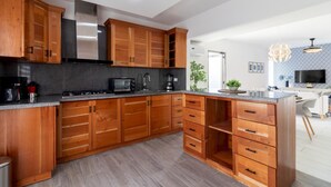 A modern kitchen with wooden cabinets, a built-in microwave, and a gas stove. - Homely 4BR Villa With Private Pool in Punta Cana (Punta Cana)