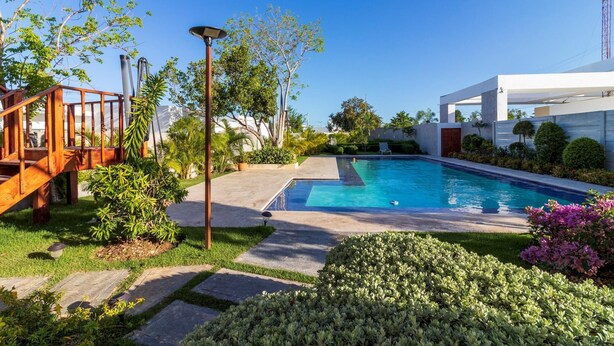 A modern outdoor pool area with a wooden deck, a lamp post, and a well-maintained garden. - Homely 4BR Villa With Private Pool in Punta Cana (Punta Cana)