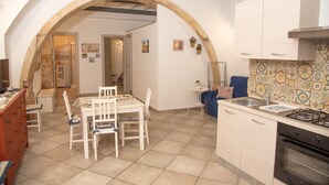A kitchen with a dining area, featuring an archway, tiled backsplash, and modern appliances. - Tiche Home 200m From Sea, Ortigia, Italy (Ortigia)