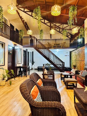 A spacious interior with a wooden staircase, wicker furniture, hanging plants, and pendant lighting. - Amancio's Balai (Puerto Princesa)