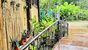 Un espace extérieur abrité, doté d’une clôture en bambou, de plantes en pot et d’une rambarde en métal.