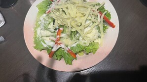 A plate of salad with lettuce, shredded cheese, and carrot sticks on a table. - Hotel Nepal Inn (Sauraha)