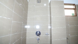 A bathroom with beige tiled walls, a showerhead, and a window. - Hotel Nepal Inn (Sauraha)