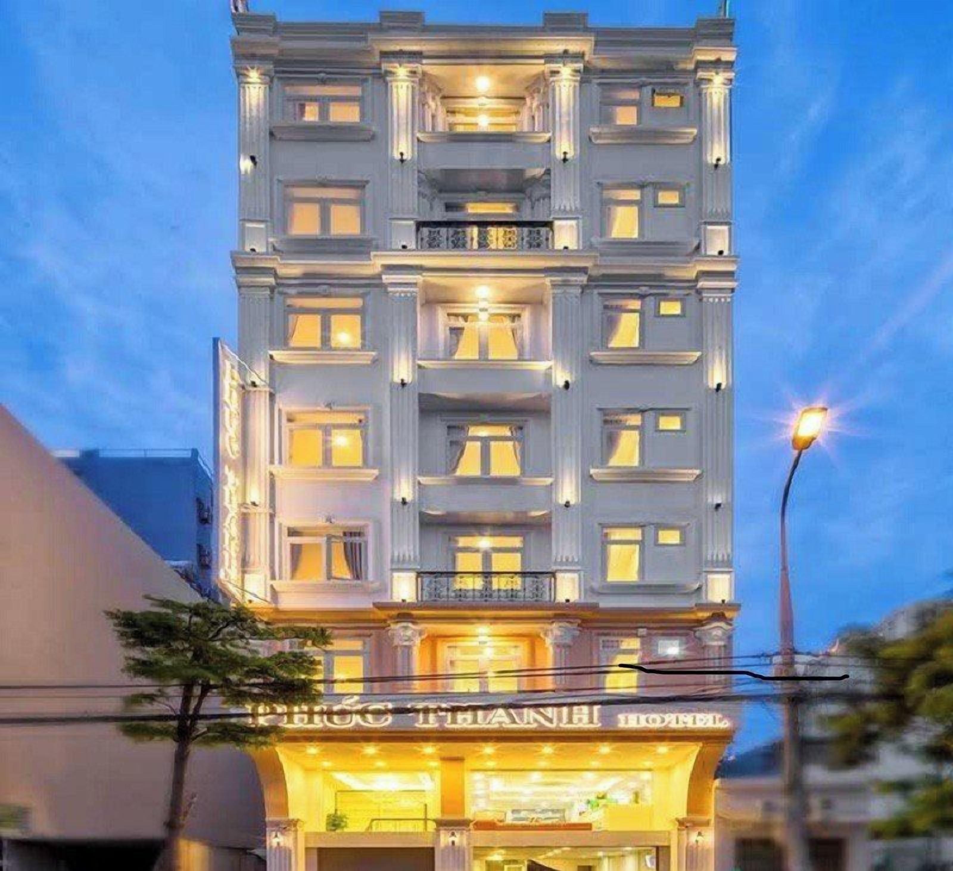 Un hotel de varios pisos con un diseño arquitectónico clásico, con balcones y una entrada bien iluminada.
