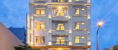 Un hôtel à plusieurs étages, doté d’une architecture classique, avec des balcons et une entrée bien éclairée.