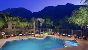 A pool area with lounge chairs and a view of mountains.