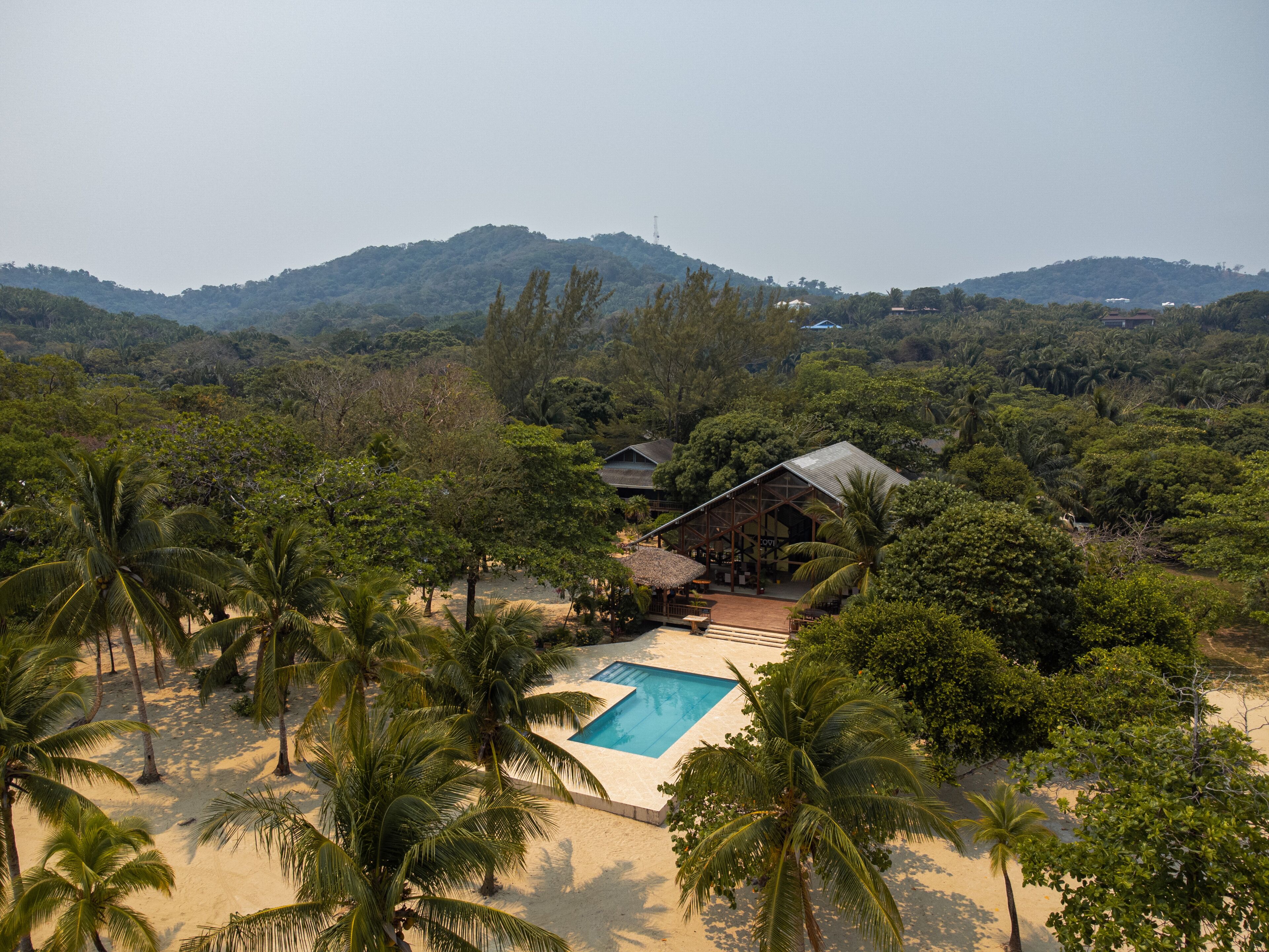 Ein Resort mit Pool, umgeben von Palmen und Bergen.