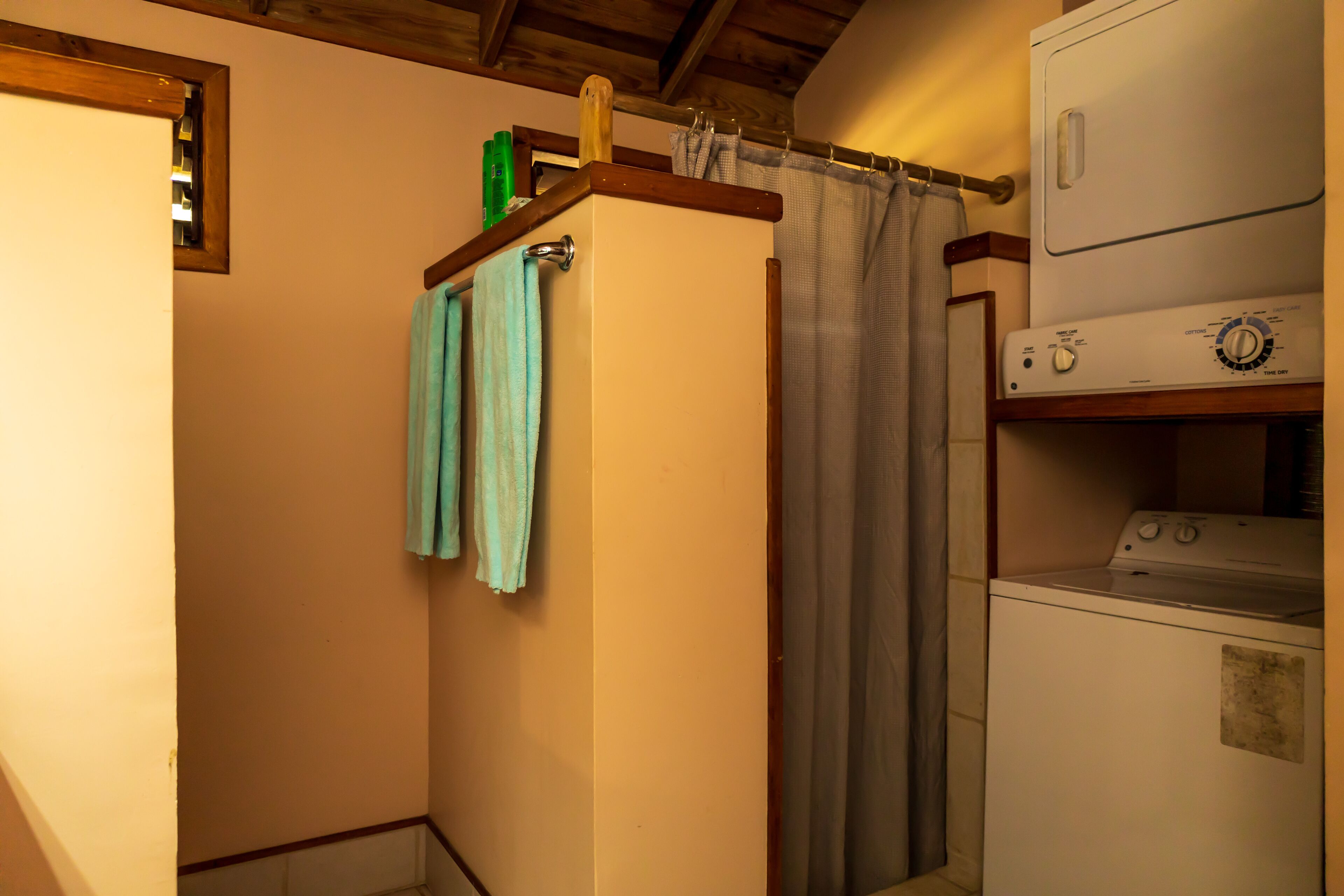 A compact laundry area with a washing machine, a dryer, and a shower curtain.