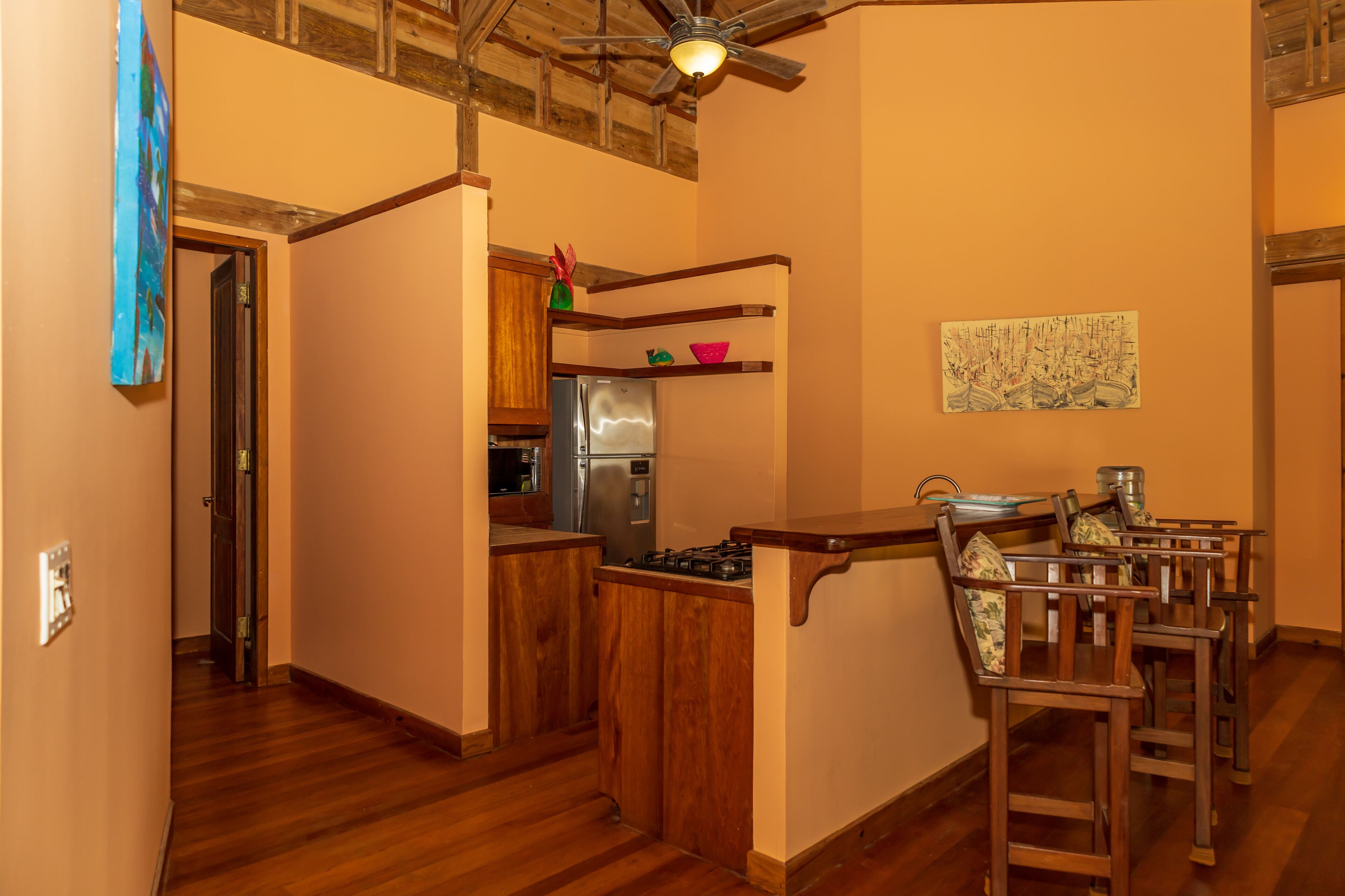 Una cocina con muebles de madera, un refrigerador de acero inoxidable y un comedor con sillas de madera.
