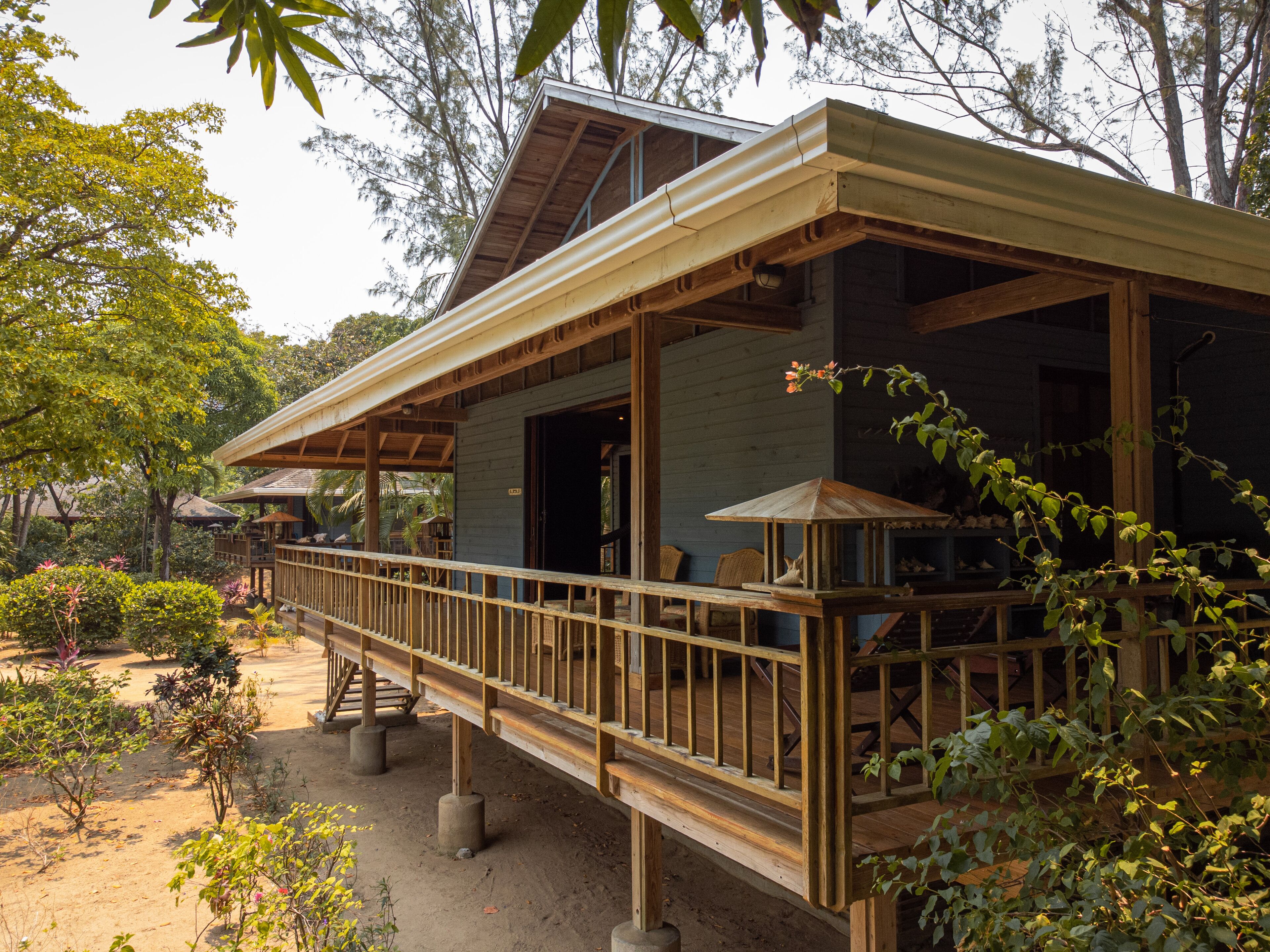 A wooden house with a balcony, surrounded by greenery.