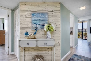 A room with a white wall, a painting of a boat, a vase with flowers, and a console table with drawers. - Ocean Views! Across from Siesta Beach, Heated Pool (Siesta Key)