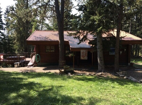 A wooden cabin with a tiled roof, surrounded by trees. - Deer Pass Lodge (Lead)