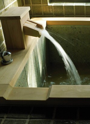 Een houten bank met een ingebouwd wasbakje en een klein metalen bekertje.
