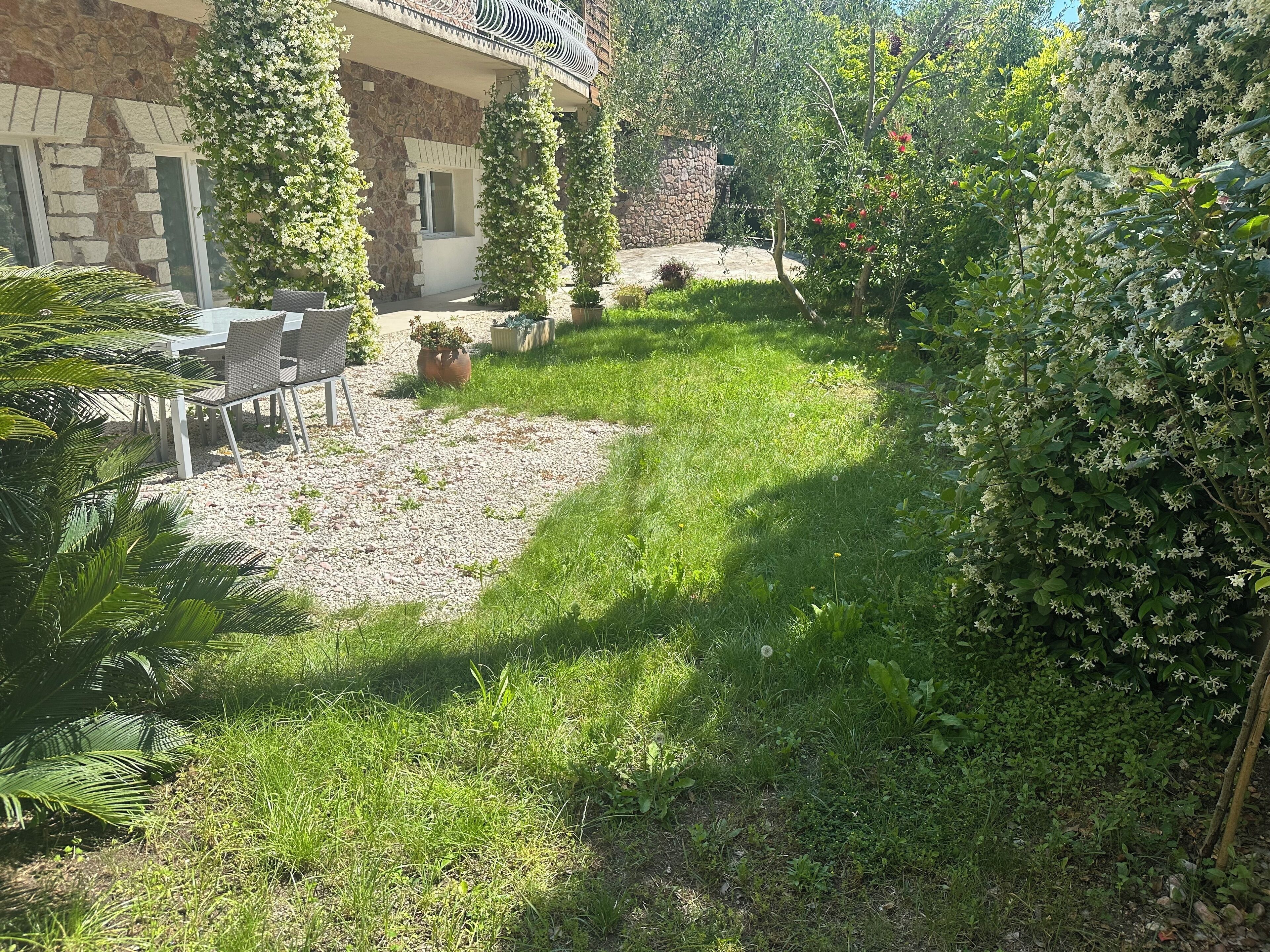 A courtyard with a stone building, outdoor seating, and lush greenery.