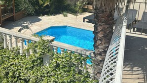 En swimmingpool omgiven av frodig grönska och en palm.