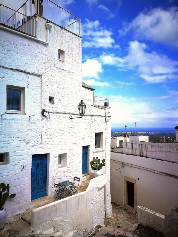 A white building with balconies, a blue door, and a cactus plant.