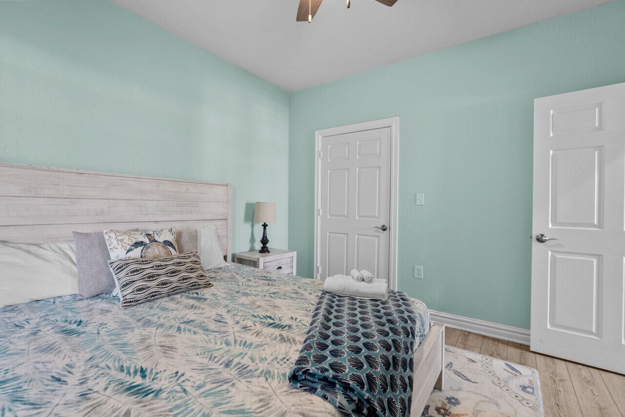 A bedroom with a bed, nightstand, lamp, and two doors.