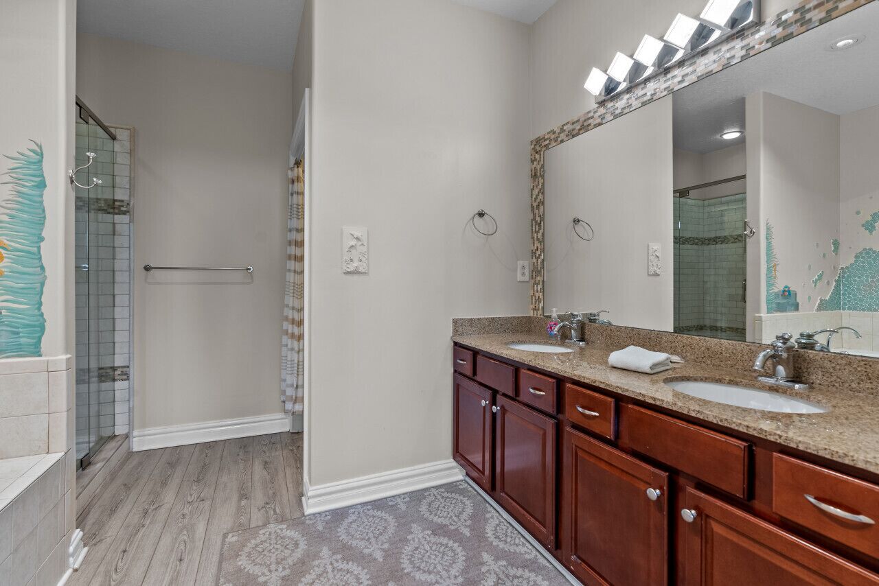 A bathroom with two sinks, a large mirror, and a shower area.