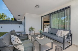 Relax in this stylish outdoor space with a sofa, coffee table, and potted plant.