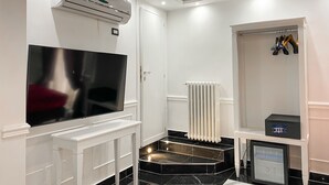 Un baño moderno con un espejo grande, un tocador blanco, un calentador incorporado y un refrigerador pequeño.