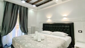 Un dormitorio moderno con una cama grande, cabecera oscura y una mesita de noche pequeña.