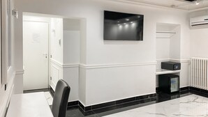 Una cocina moderna con encimera de mármol, una silla negra, un televisor de pantalla plana montado en la pared y un horno empotrado.