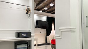Una habitación de hotel moderna con televisión de pantalla plana, minibar, una silla roja y un espejo grande.