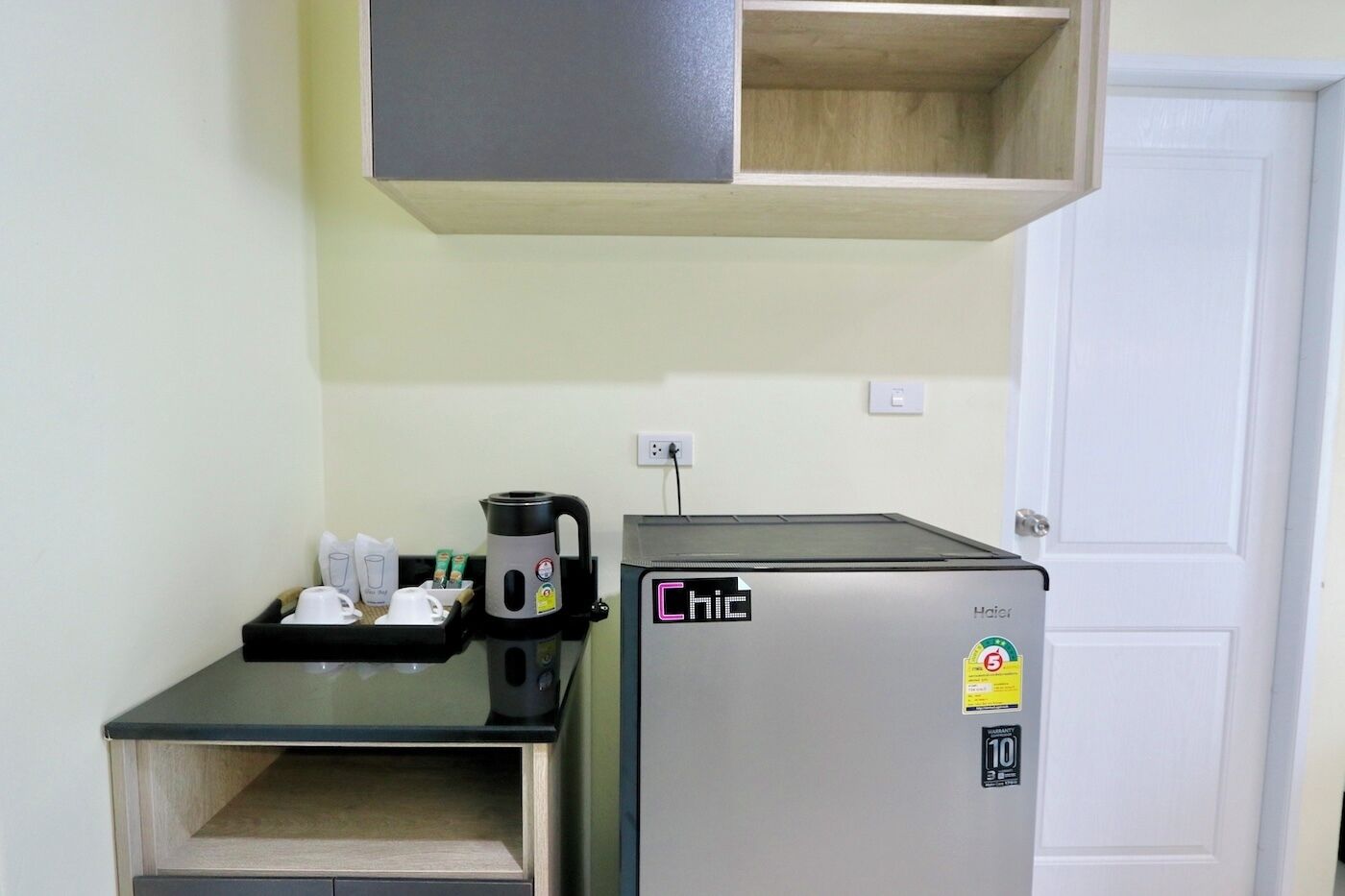 A compact kitchenette with a coffee maker, a kettle, and a refrigerator.
