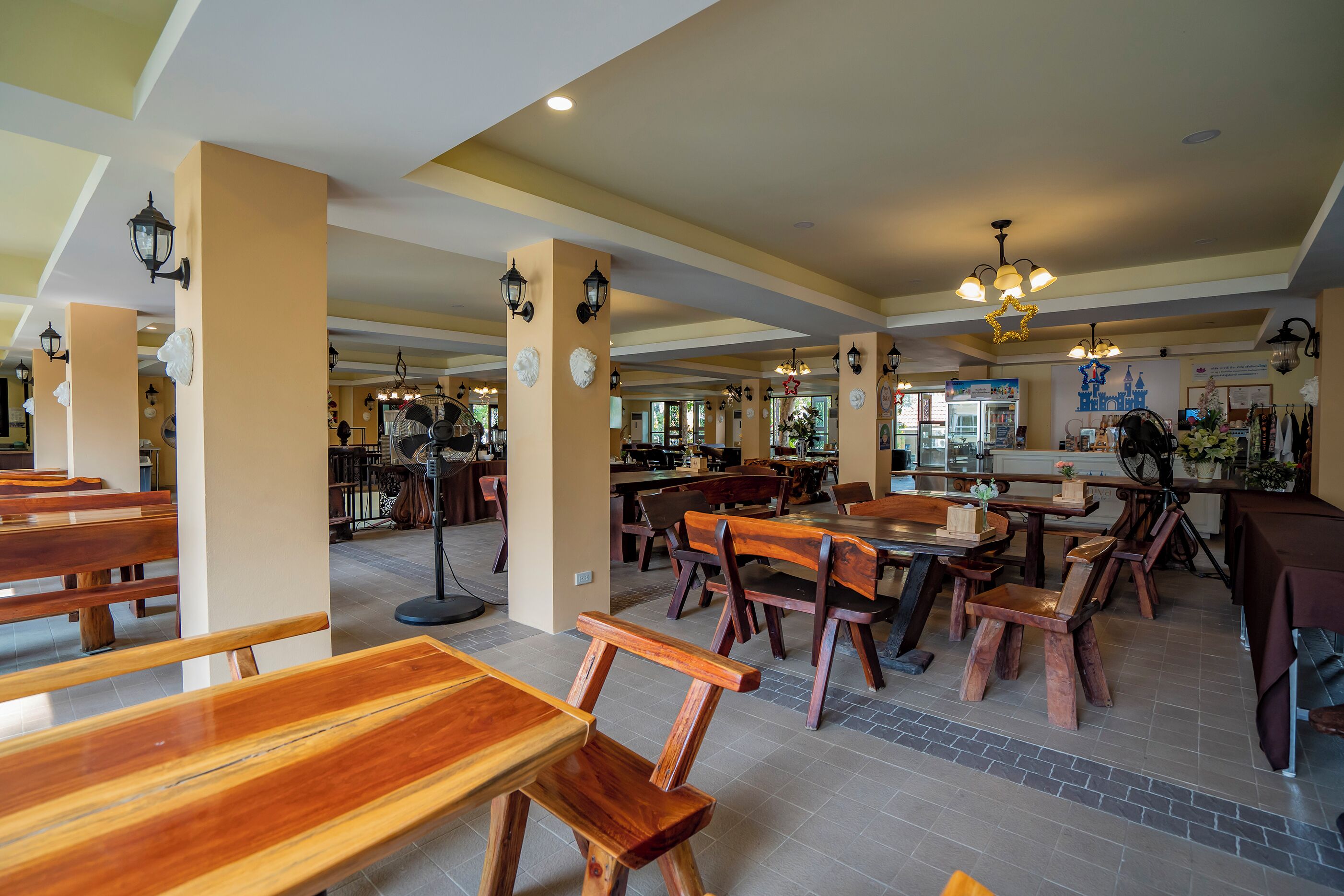 A spacious restaurant with high ceilings, wooden furniture, and decorative wall sconces.