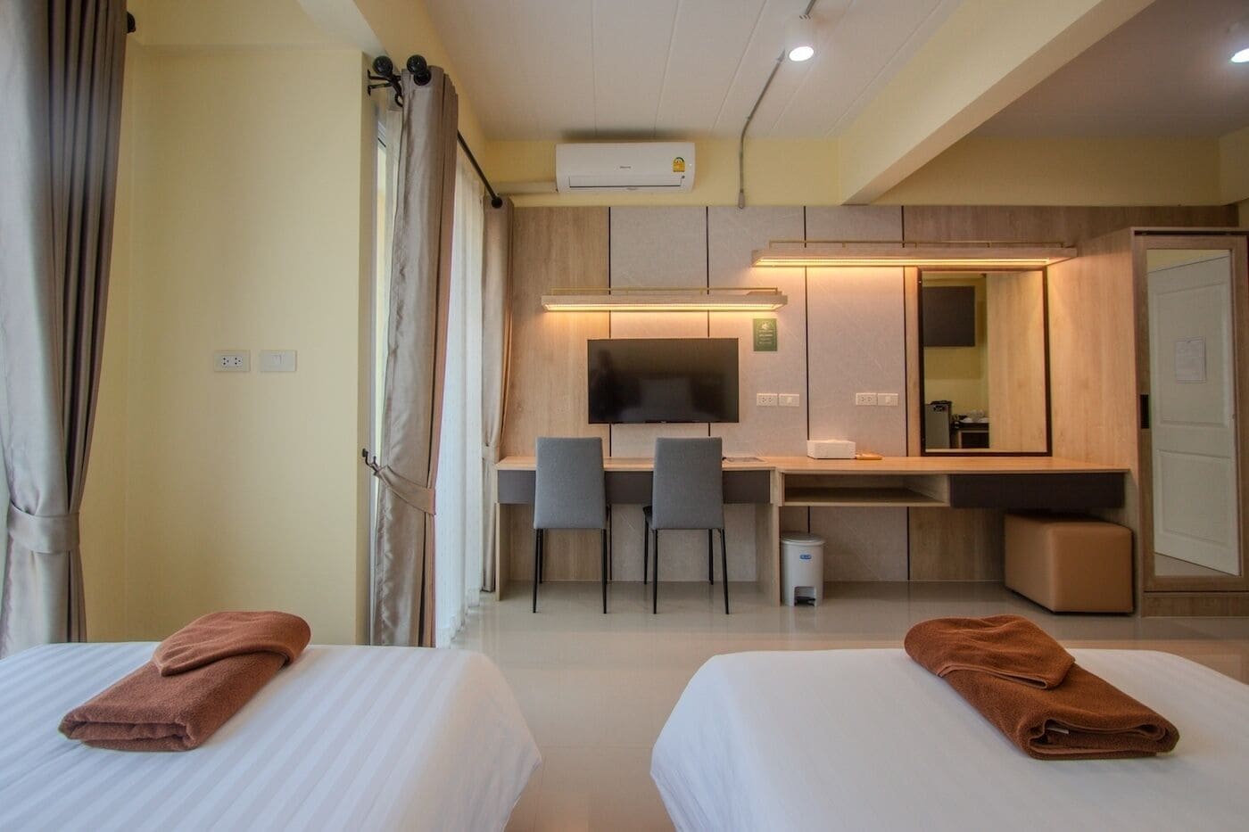 Een hotelkamer met twee bedden, een bureau, een televisie en een badkamer.
