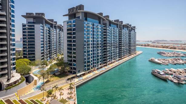 Un hotel moderno de gran altura con varios balcones y un puerto deportivo con barcos.