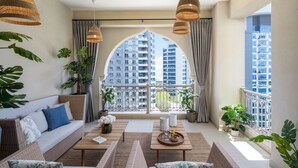Un balcón amplio con vistas a rascacielos, amueblado con un sofá, una mesa de centro y plantas en macetas.