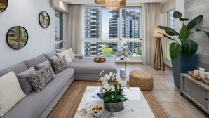 Una sala de estar moderna con un sofá gris, una mesa de centro con una planta y un ventanal con vistas a la ciudad.