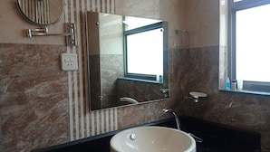 A bathroom with a round mirror, a rectangular mirror, a sink, and a window. - Janaki House (Burhanilkantha)