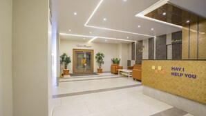 A hotel reception area with a modern design, featuring a reception desk, seating area, and a door labeled "Kahook Banquet."