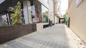 A paved walkway with a storefront on the left and a building entrance on the right.
