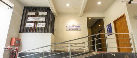 A hotel entrance with a staircase, a sign for 'Kadison Hotel', and a no smoking area sign.