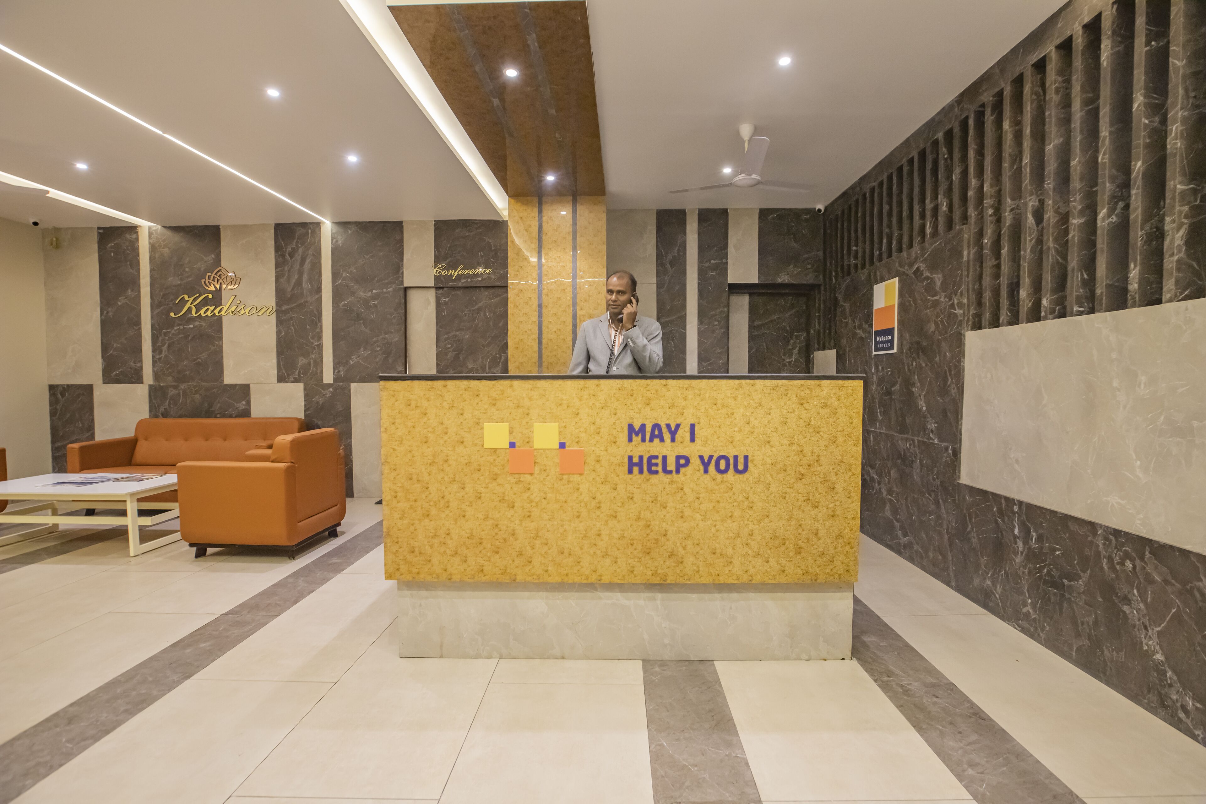 A reception area with a marble wall, a reception desk, and a sofa.